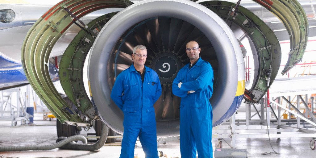 Two mechanics standing in front of a jet propeller