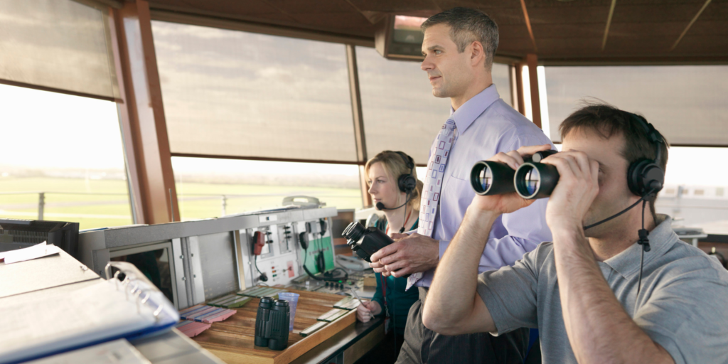 Two men and a woman looking out of an Air Traffic Control Tower